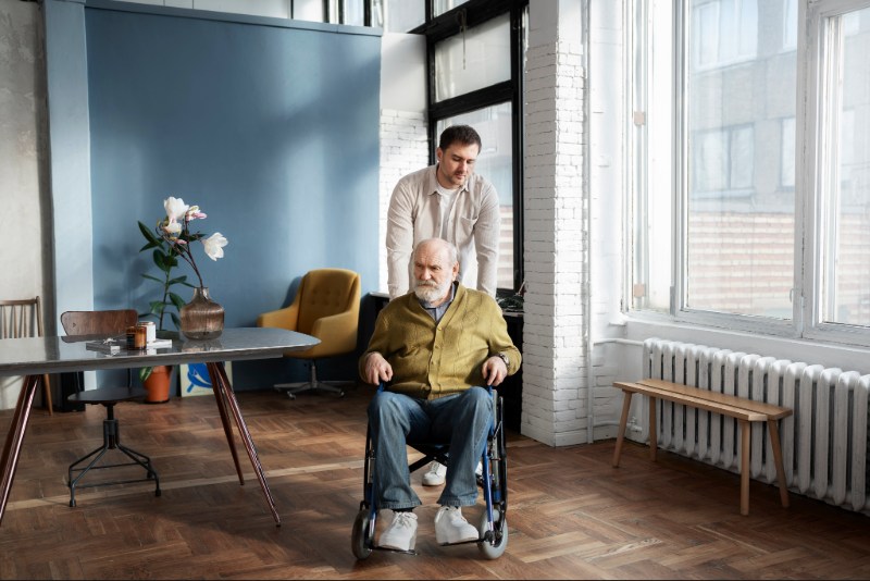 SIL Accommodation in WA 01 - An elderly disabled man assists the Blisscare personnel in his wheelchair.